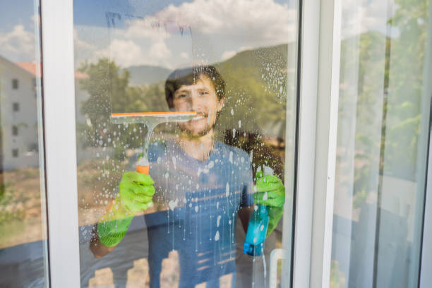 istock A young man cleaning the window with a window cleaner 1457608434