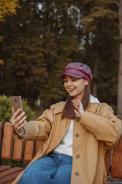 uśmiechnięta kobieta prowadząca rozmowę wideo na smartfonie w publicznym parku - seat row obrazy zdjęcia i obrazy z banku zdjęć