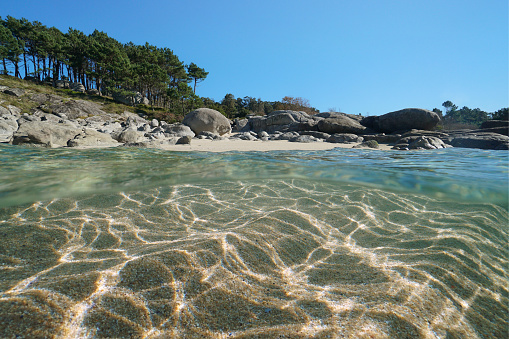 Beach with sand and rocks, sea shore over and under water surface, split level view, Atlantic ocean, Spain, Galicia, Rias Baixas