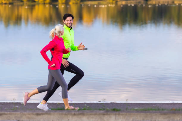 istock Jogging Concepts. Running Couple While Training Outdoors on Road At River For Durable Marathon Pretty Young Female and Extremely Fit Caucasian Handsome Man in Their Prime. 1457611501