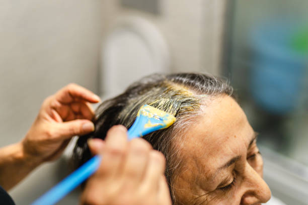 peluquero voluntario tiñe el cabello de una mujer mayor en casa - white hair fotografías e imágenes de stock