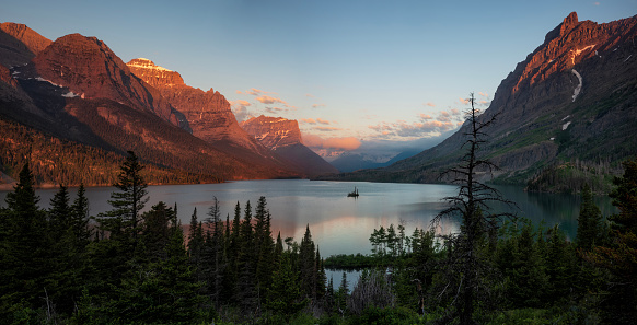 Wild Goose Island, located on the second largest lake in Glacie National Park, Saint Mary Lake, floats in the placid waters that surrounds it during a sunrise.