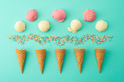 Ice cream, cones and sprinkles on a green background.