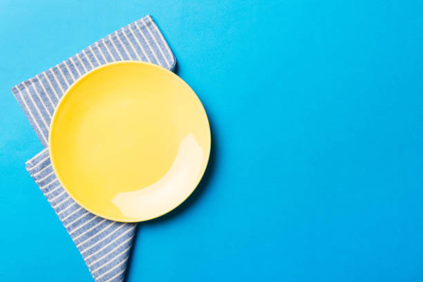 istock Top view on colored background empty round yellow plate on tablecloth for food. Empty dish on napkin with space for your design 1457622094