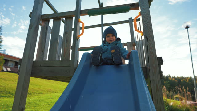 Cute little boy in hat prepares to slide on playground