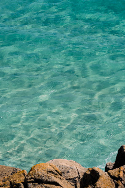 istock Views down from the cliffs onto the clear blue sea at Porthcurno, South Cornwall on a bright June day. 1457628965