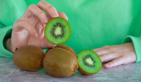Young woman holding kiwi fruit in her hand. Healthy lifestyle concept. Closeup photo.