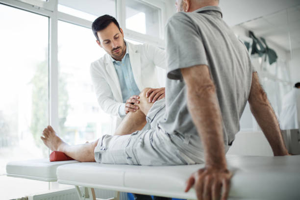 ältere mann mit seinem knie von einem arzt untersucht. - osteoarthritis doctor medicine healthcare and medicine stock-fotos und bilder