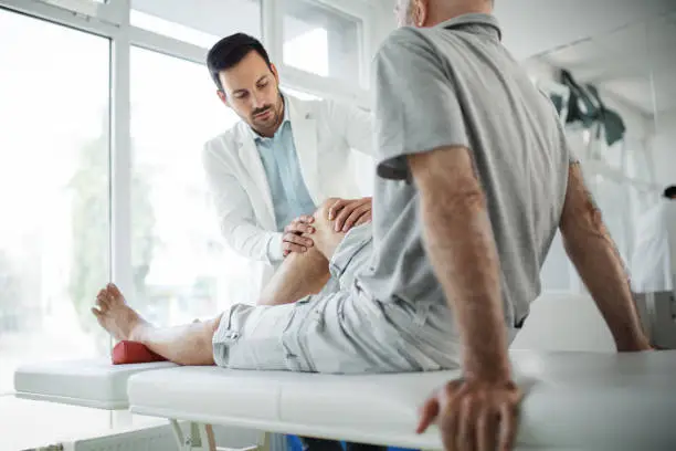 Photo of Senior man having his knee examined by a doctor.