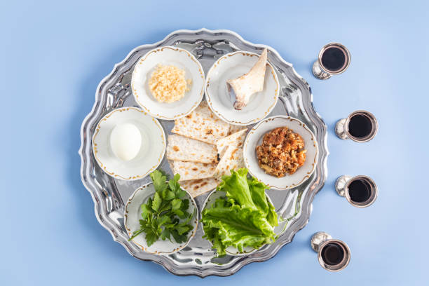 a pesach plate with traditional symbols of the Jewish Passover and four glasses of red kosher wine. top view. blue background. a pesach plate with traditional symbols of the Jewish Passover and four glasses of red kosher wine. top view. blue background horseradish stock pictures, royalty-free photos & images