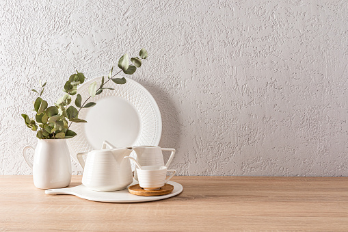 items for the tea ceremony on the kitchen wooden countertop. a branch of eucalyptus in a white vase. minimalist kitchen background with a copy space