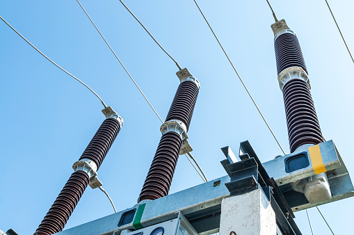 Part of high-voltage substation on blue sky background with switches and disconnectors. Ukrainian energy infrastructure.