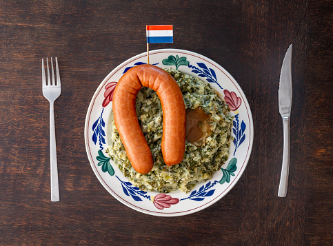 Traditional dutch 'Stamppot Boerenkool met worst' isolated on the wooden table