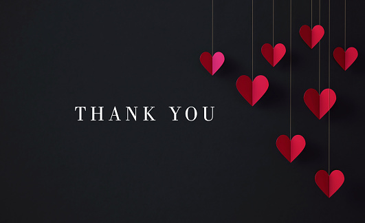 Thank you message next to hanging red heart shapes on black background. Horizontal composition with copy space.