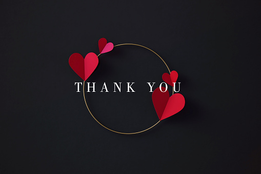 Thank you message over red heart shapes and gold colored circle on black background. Horizontal composition with copy space.