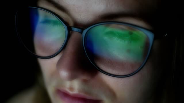Girl works on internet. Reflection at the glasses from laptop. Close up of woman's eyes with black female glasses for working at a computer. Eye protection from blue light and rays.