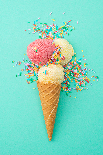 Ice cream, cones and sprinkles on a green background.