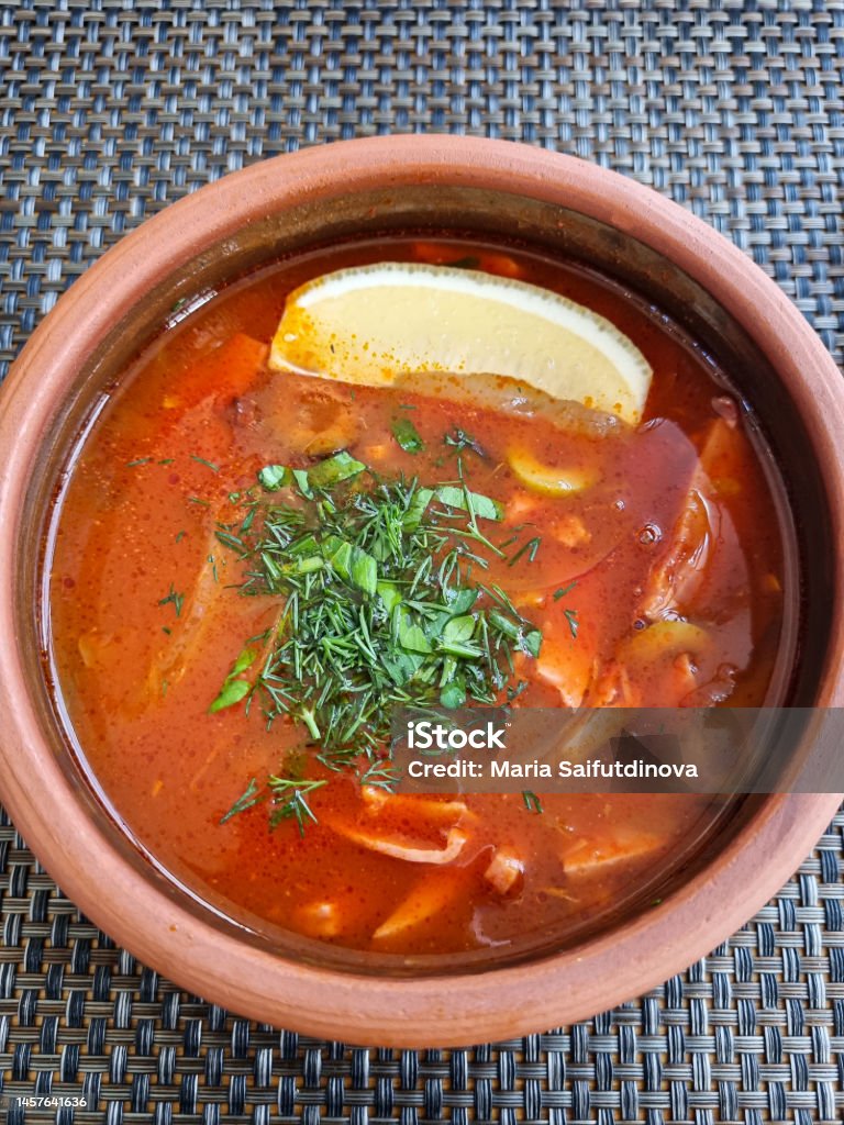 a hodgepodge soup with lemon in a clay cup. view from above. a hodgepodge with lemon in a clay cup. simple and delicious soup on the restaurant's menu. Bowl Stock Photo