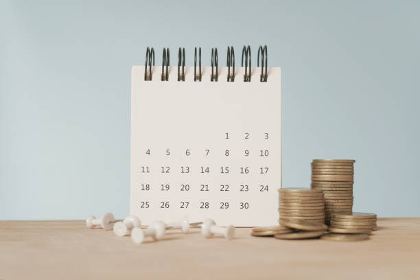 istock For payday loan concept. White calendar and blurred stack of coins , blurred white thumbtack on wood desk 1457642930