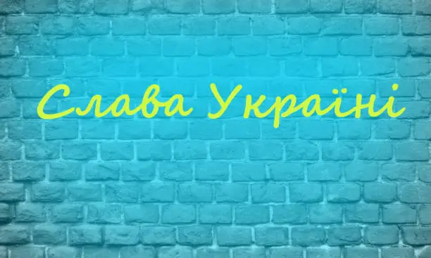 Brick blue wall with yellow inscription GLORY to Ukraine on Ukrainian language. Patriotism concept