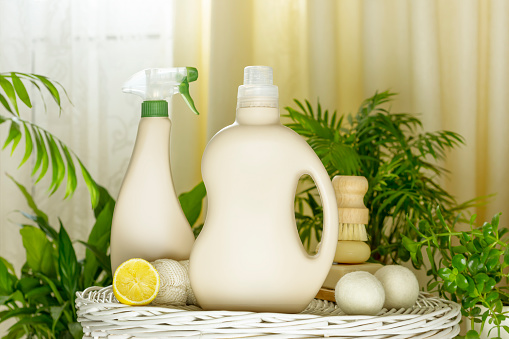Botellas de detergente con jabón, limón y cepillo en el podio de madera en el interior del hogar photo