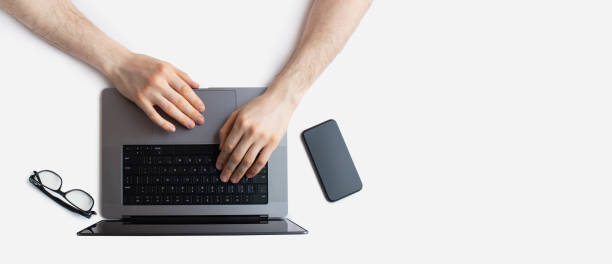 istock White desktop with laptop and male hands 1457644748
