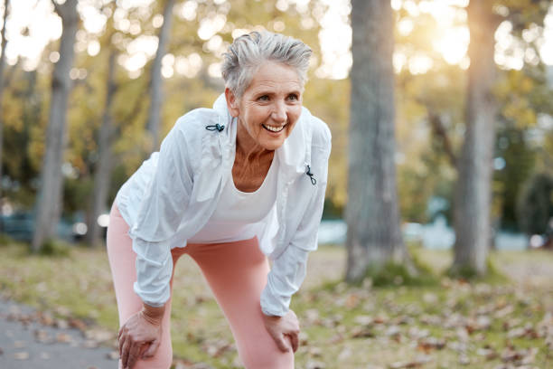 tired, happy and senior woman running in outdoor nature park for retirement health, wellness and fitness workout. healthcare exercise, path and runner with fatigue training for elderly marathon race - old senior adult women tired imagens e fotografias de stock