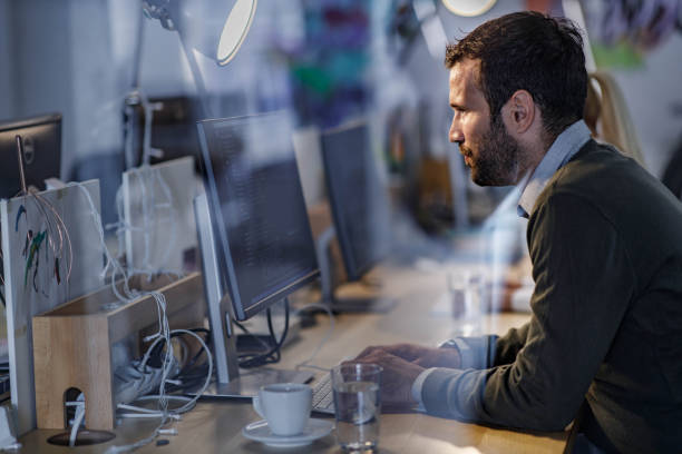 istock Profile view of a male programmer reading codes on a PC in the office. 1457646334