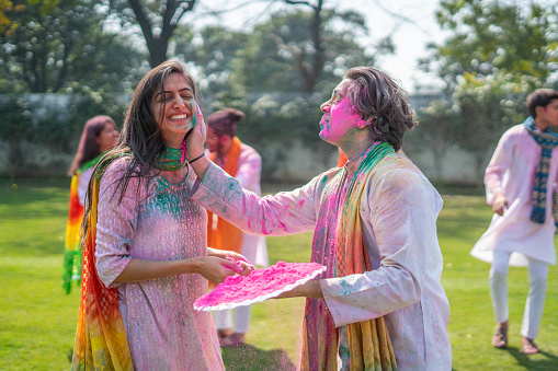 Indian man putting Holi color on his wife face
