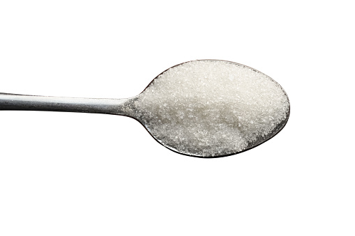Teaspoon with sugar on a white background, top view.