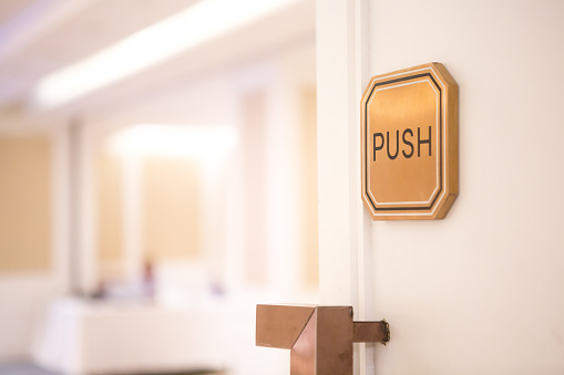 Selective focus of Push sign on the white door of the seminar room.