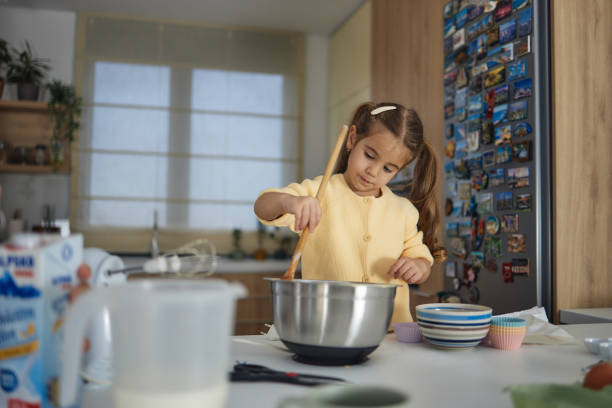 istock Young girl stands at the kitchen table making cakes 1457652795