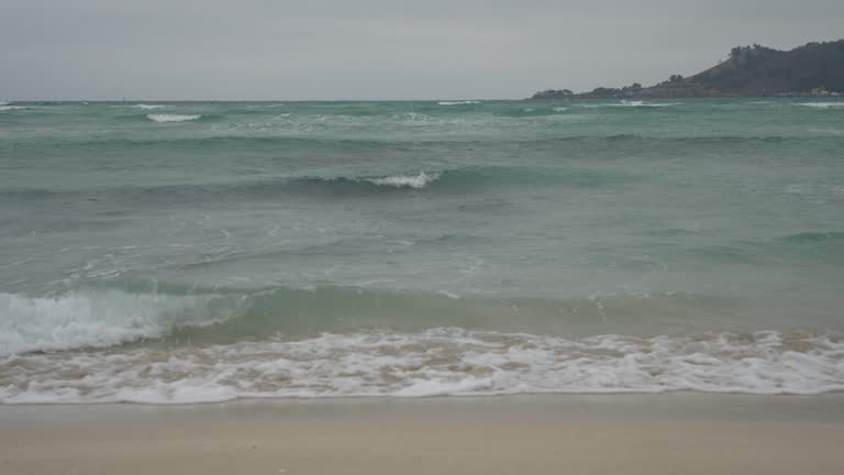 Sand and waves at Jeju Island Beach in Korea on a windy and cloudy day