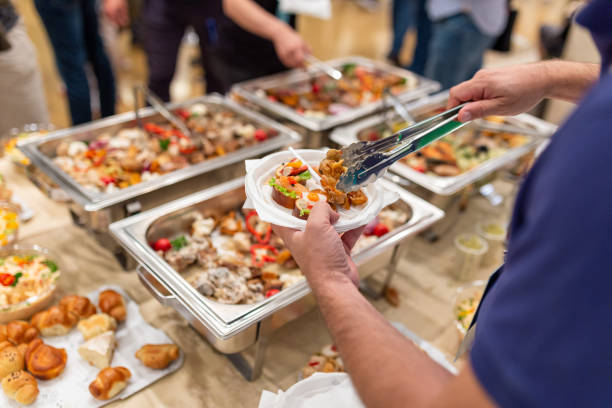 istock Man holding plastic plate and scooping food at buffet table catering in hotel or restaurant 1457654942