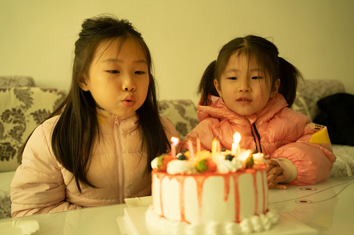 Asian children blowing out candles