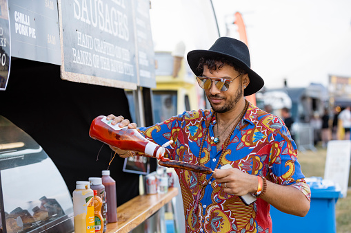 Man putting ketchup on a hot dog he has bought from a food stall at a festival in Northumberland, North East England.