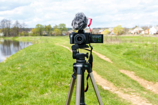 istock Digital camera with microphone on a tripod close-up. Mirrorless digital camera and microphone recording while broadcasting in nature 1457662831