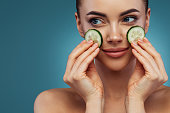 Happy young girl with facial mask of cucumbers on her face