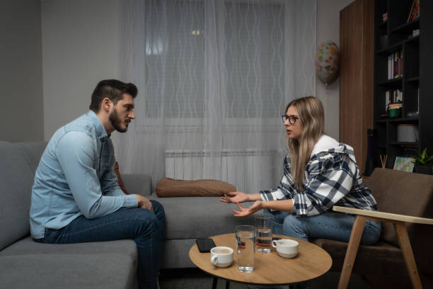Young married couple husband and wife sitting at home having problems in their marriage and a cold relationship. A boyfriend and a girlfriend have an argument about spending too much money. stock photo