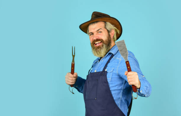istock happy hipster hold cooking utensils for barbecue. bearded man chef. Tools for roasting meat outdoors. Picnic and barbecue. ready for barbecue party. Culinary concept. summer weekend. copy space 1457666013