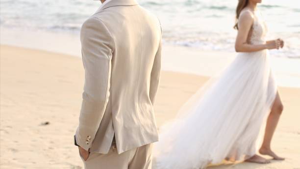 istock Bride and groom walking on the beach 1457667453