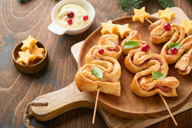 istock Christmas or New Year appetizer. Christmas tree shape puff pastry buns with cheese and ham. Group of Christmas tree shapes on wooden board. Festive idea for Christmas or New Year dinner. Top view. 1457668666