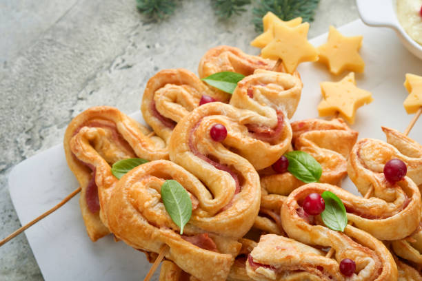 istock Christmas or New Year appetizer. Christmas tree shape puff pastry buns with cheese and ham. Group of Christmas tree shapes on marble stand. Festive idea for Christmas or New Year dinner. Top view. 1457668721