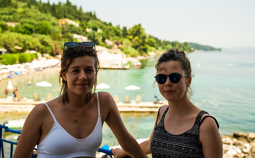Two women in a tourist resort posing for a portrait. Enjoying hot summer weather and beautiful sun
