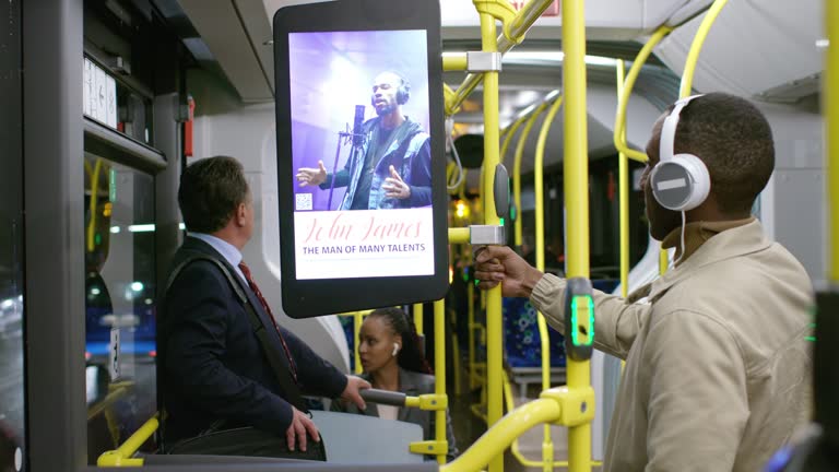 Woman sitting on the bus and looking at an advertisement on the screen