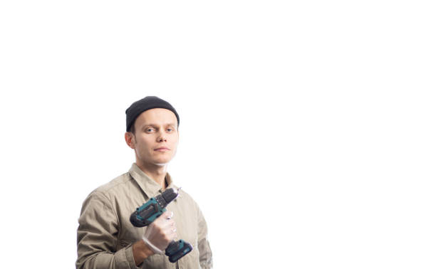 An African man in a blue overall holding a cordless drill