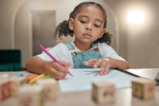 Girl, homework and writing on paper, learning and homework with math, education and knowledge at table in home. Latino child or student in brazil with concentration, school work and study in house