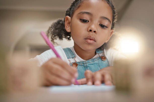 istock Student, child learning and writing in notebook for development, fine motor skills and home schooling. Education, knowledge study and kid creative drawing or write on paper with pencil on home desk 1457679619