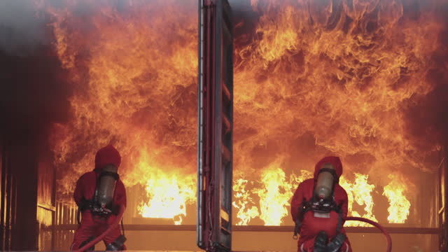 Slow Motion of firemen using fire hose to extinguish a fire Inside burning building.