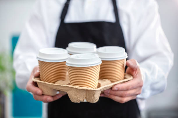 barista cameriere che tiene una tazza di caffè caldo usa e getta di carta da asporto nel bar - disposable cup plastic recycling cup foto e immagini stock